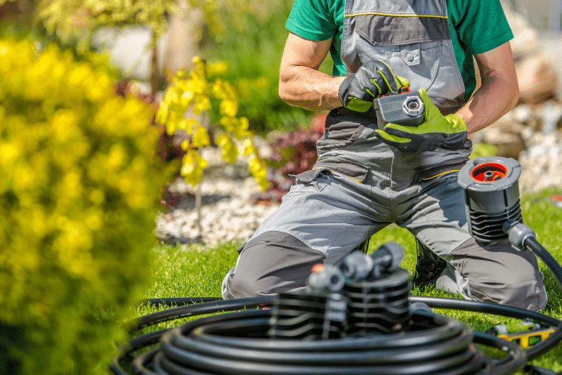 Technician performing irrigation system final inspection on residential sprinkler system in backyard