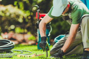 Technician performing irrigation system final inspection on residential sprinkler system in backyard lawn
